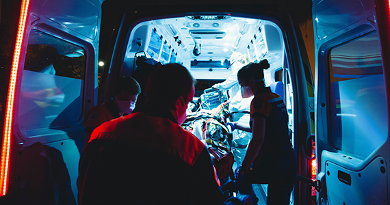 Image of a person being lifted into the back of an ambulance. 